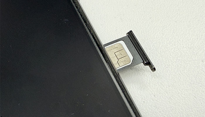 iPhoneのSIMカードをソケットから出している