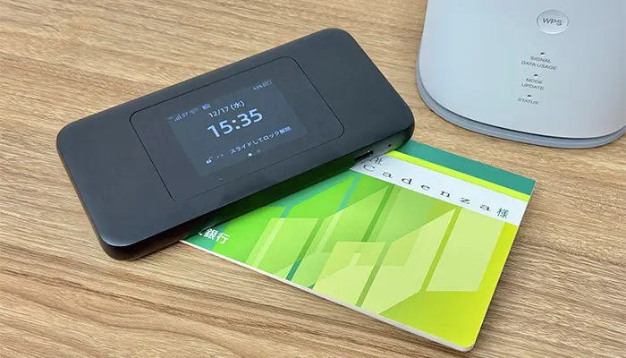 銀行の通帳とWiMAXのモバイルルーターとホームルーターが並べて置いてある写真